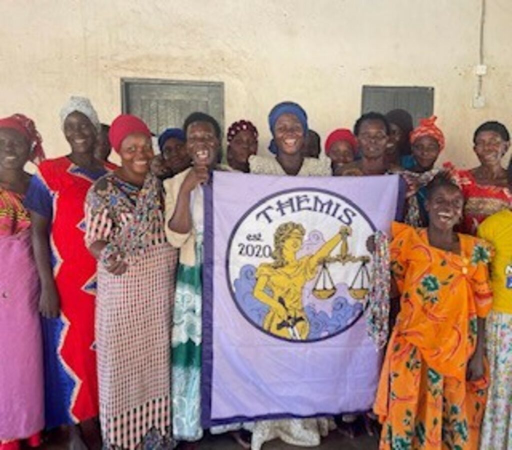 group of women in traditional dress holding themis banner